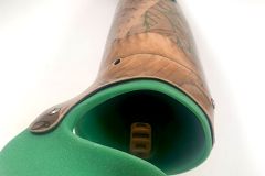 This 14ELMT custom transradial prosthesis features a laminated fabric sleeve over a carbon fiber frame featuring a woodland image and a coordinating green silicone socket. It is paired with a TASKA Hand.